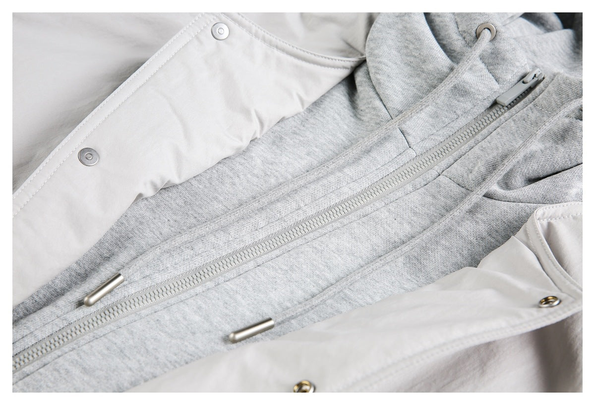 Close-up of an open pale gray outer layer revealing a gray hooded inner layer with a front zipper and drawstrings.
