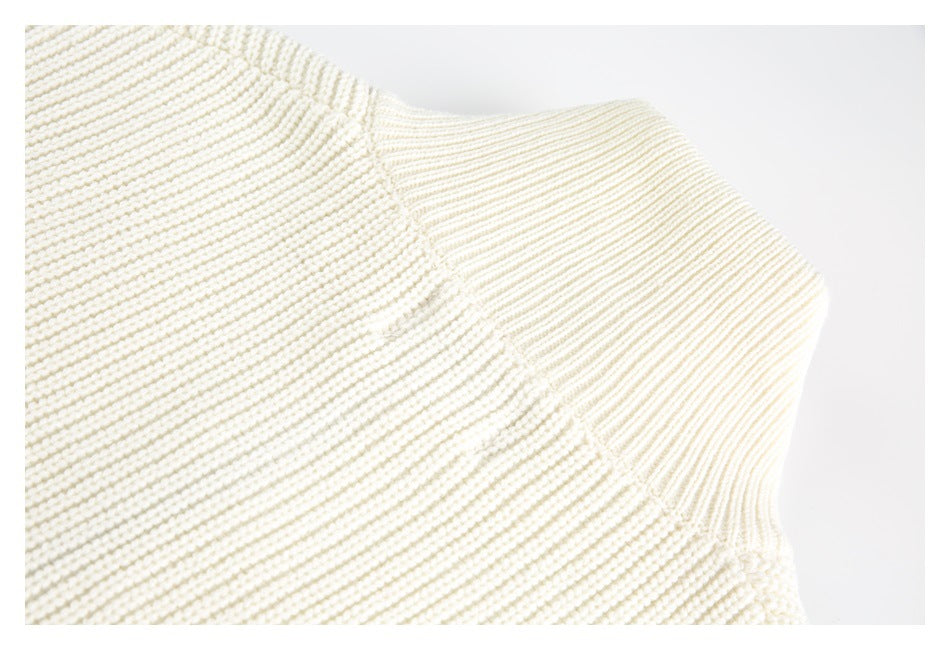 Close-up of a seam joining ribbed and textured sections of an ivory knit garment.