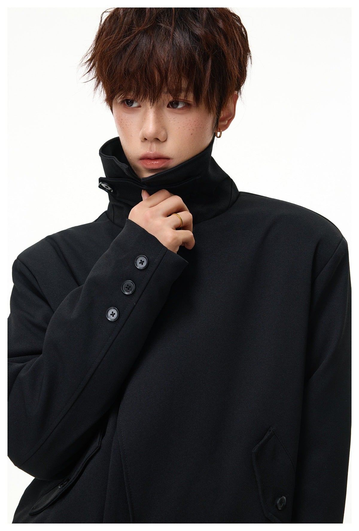 Close view of the black jacket's raised collar, angled closure, and three-button sleeve cuff.