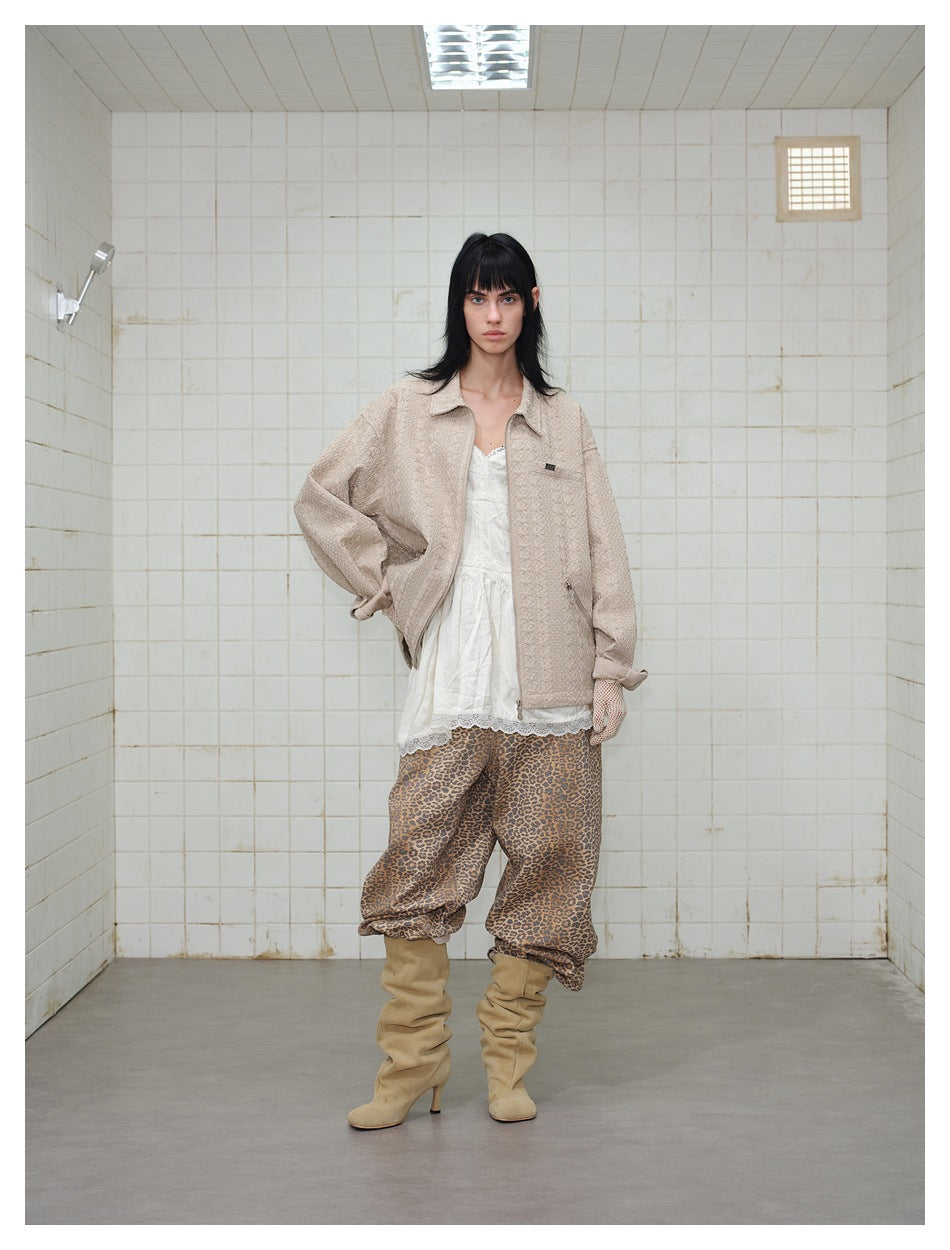 Front view of a person wearing an open beige textured jacket over a white lace-trim top and leopard-print pants.