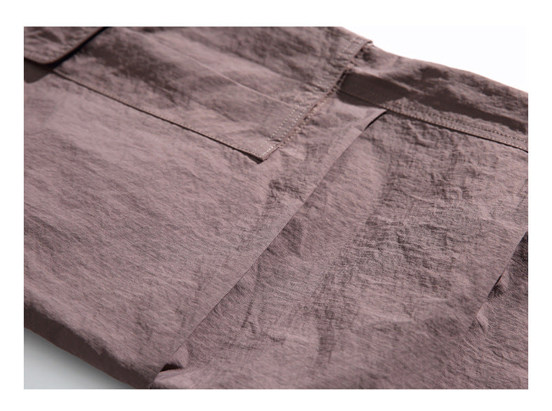 Close-up of brown shorts showing the textured fabric and a stitched pocket flap.