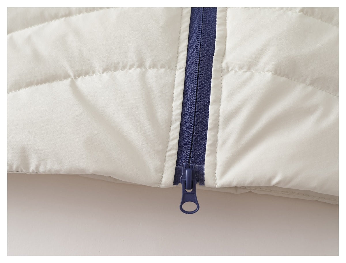 Close-up of a dark blue zipper and pull at the hem of a white quilted jacket.