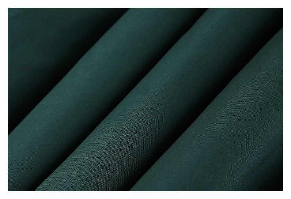 Macro view of dark green fabric folded into broad diagonal ridges.