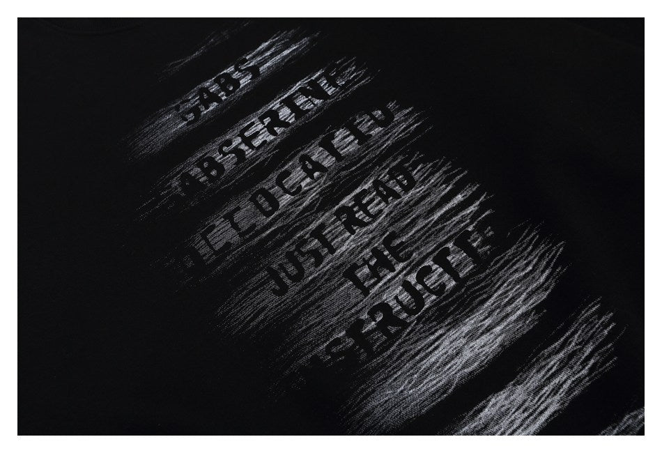 Close-up of black fabric with distressed gray English lettering printed diagonally.