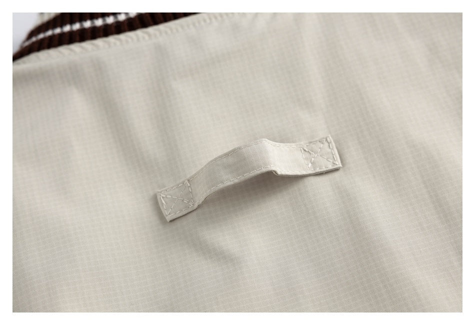 Close-up of a small beige fabric tab with reinforced stitching on the jacket.