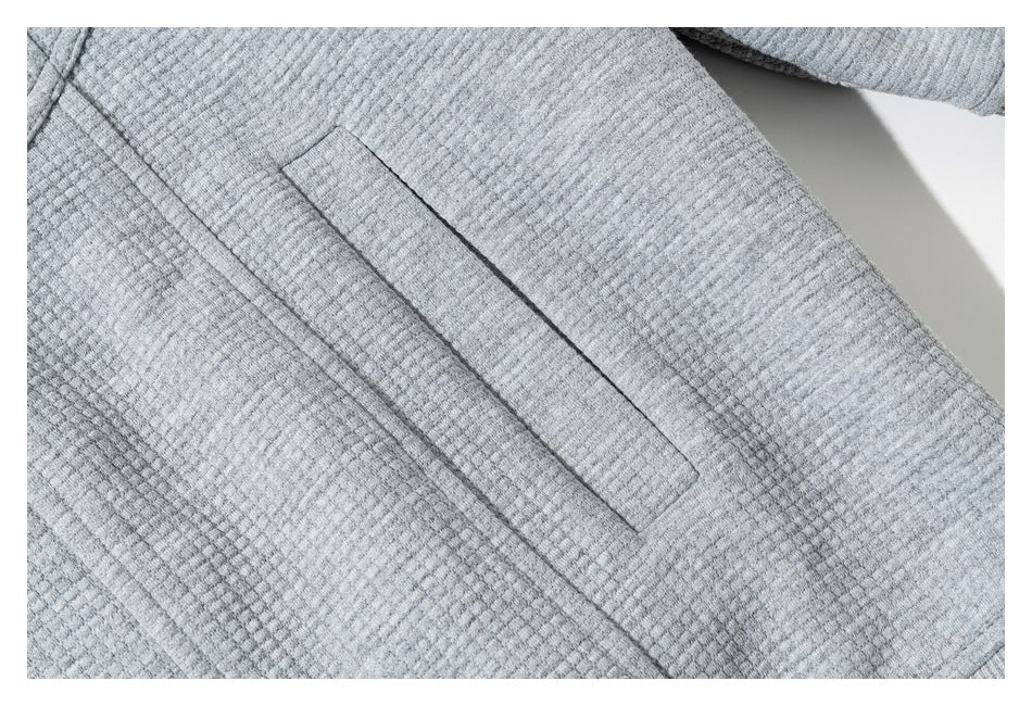 Close-up of a narrow welt pocket on the textured gray sweatshirt.