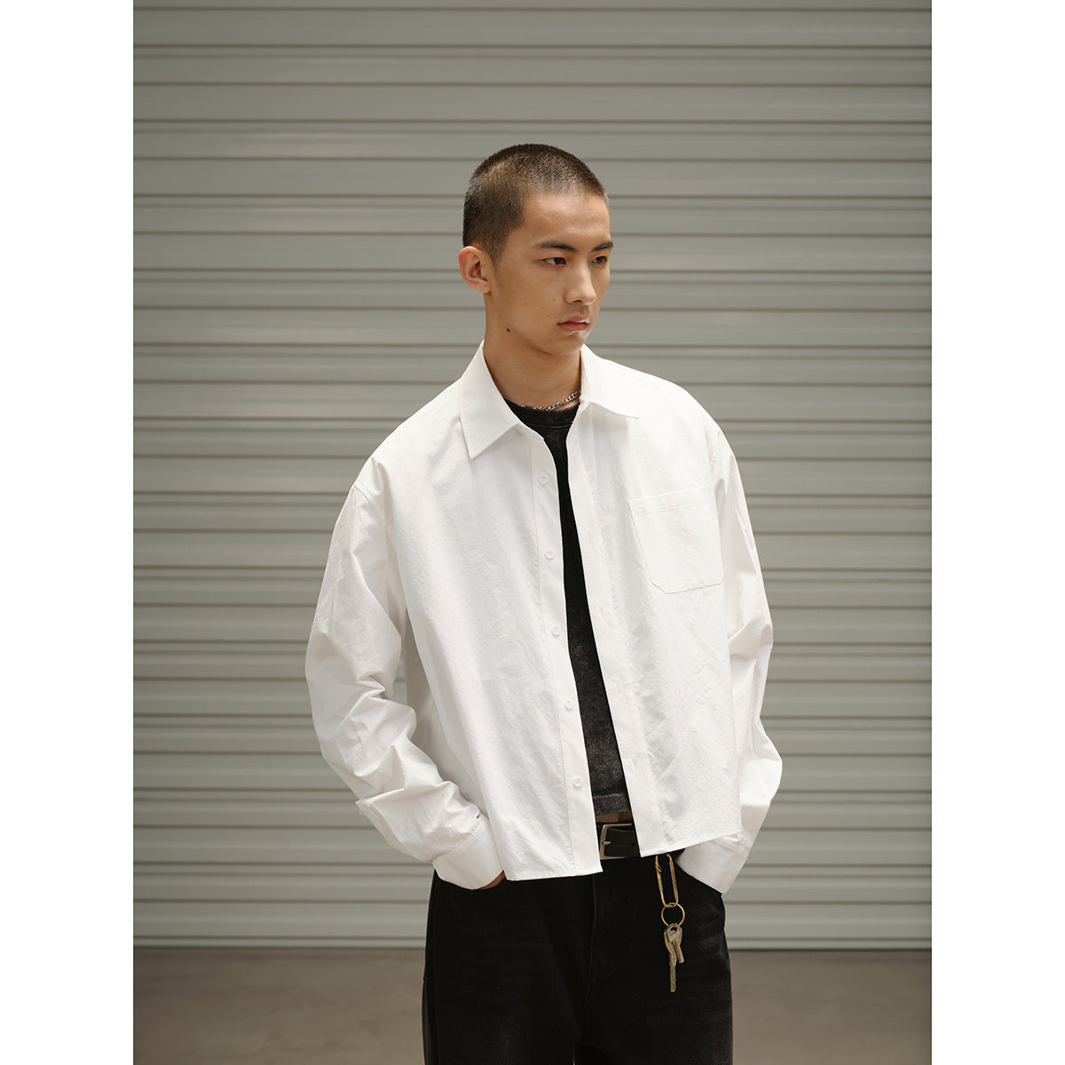 Model wearing a white long-sleeve button-up shirt with a chest pocket over a black tee.