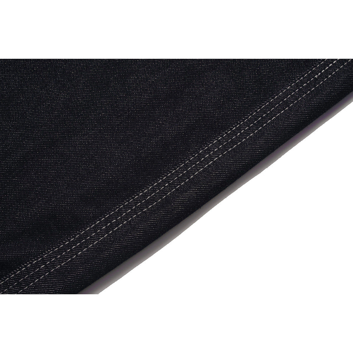 Close-up of dark denim fabric and a diagonal double-stitched hem.