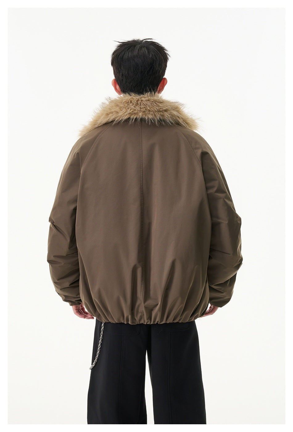 Rear view of a model wearing a brown jacket with a tan fur collar and gathered hem.