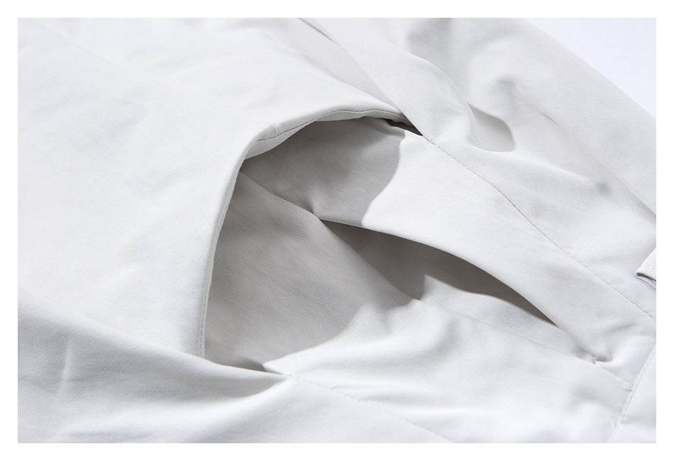 Close-up of the curved pocket opening and seams on pale gray trousers.