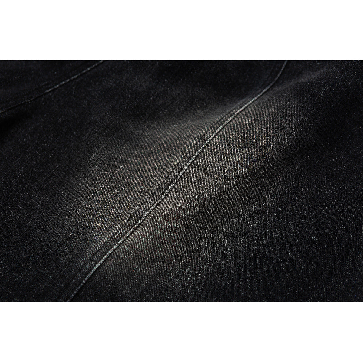 Close-up of black fabric showing a diagonal stitched seam and fine texture.