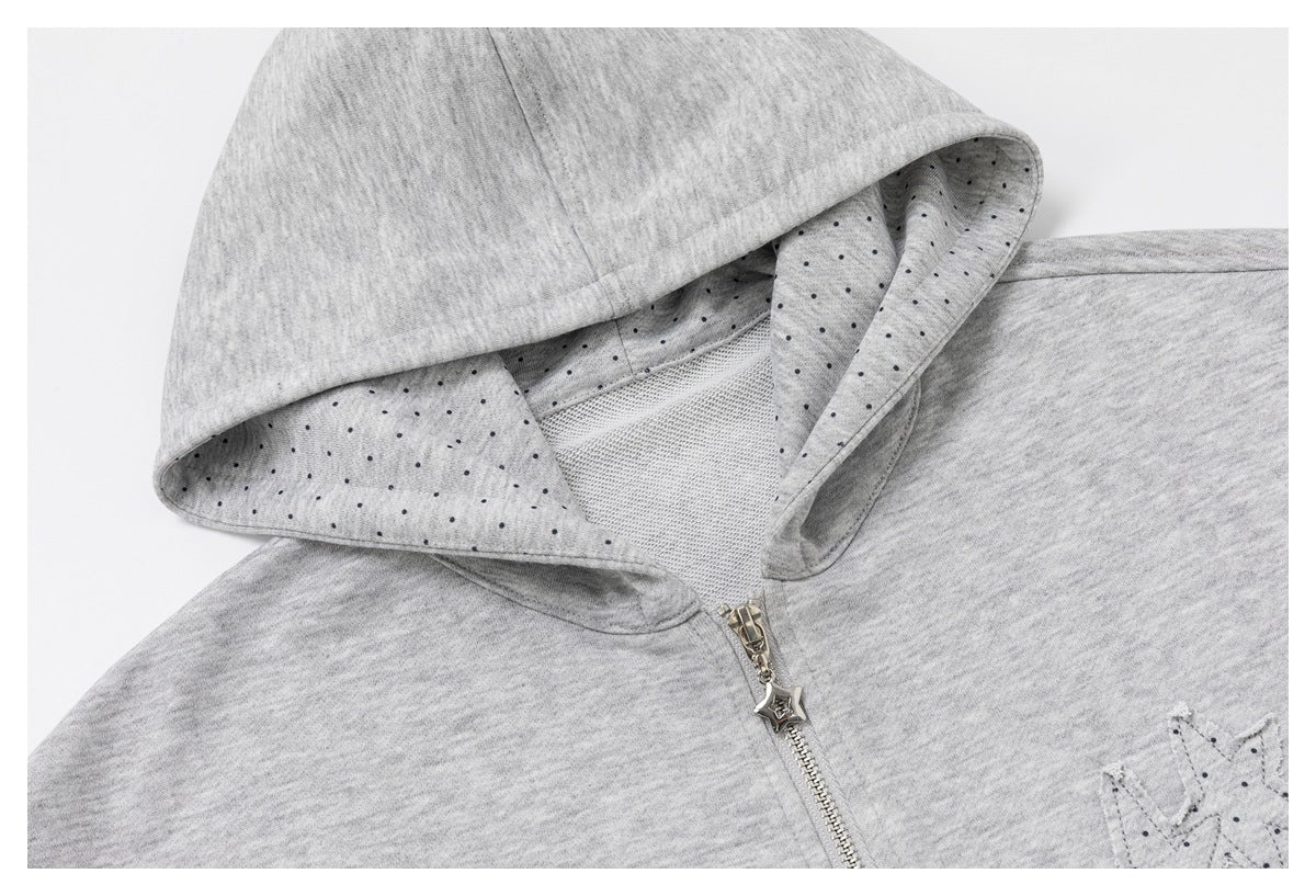 Close-up of the gray hoodie showing its dotted hood lining, silver star zipper pull, and embroidered chest motif.
