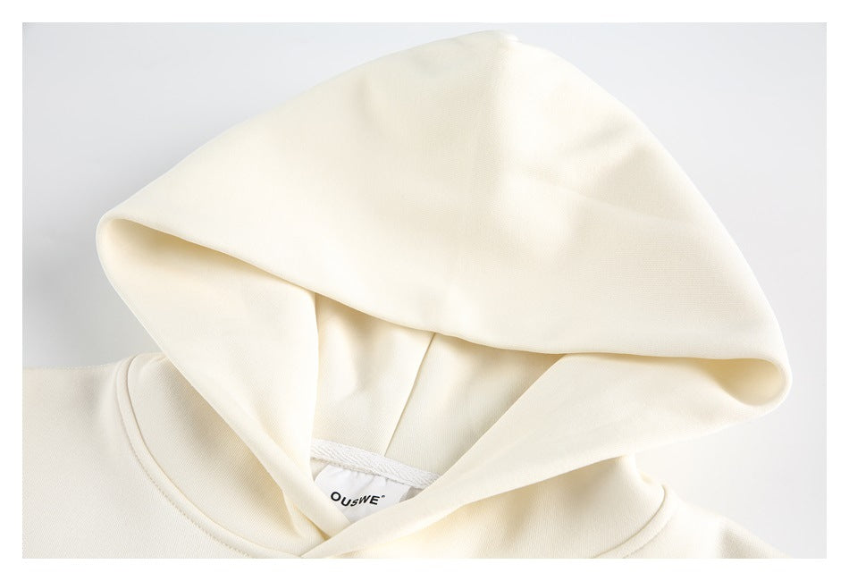 Close-up of an ivory hoodie showing the hood, neckline, and inner neck label.