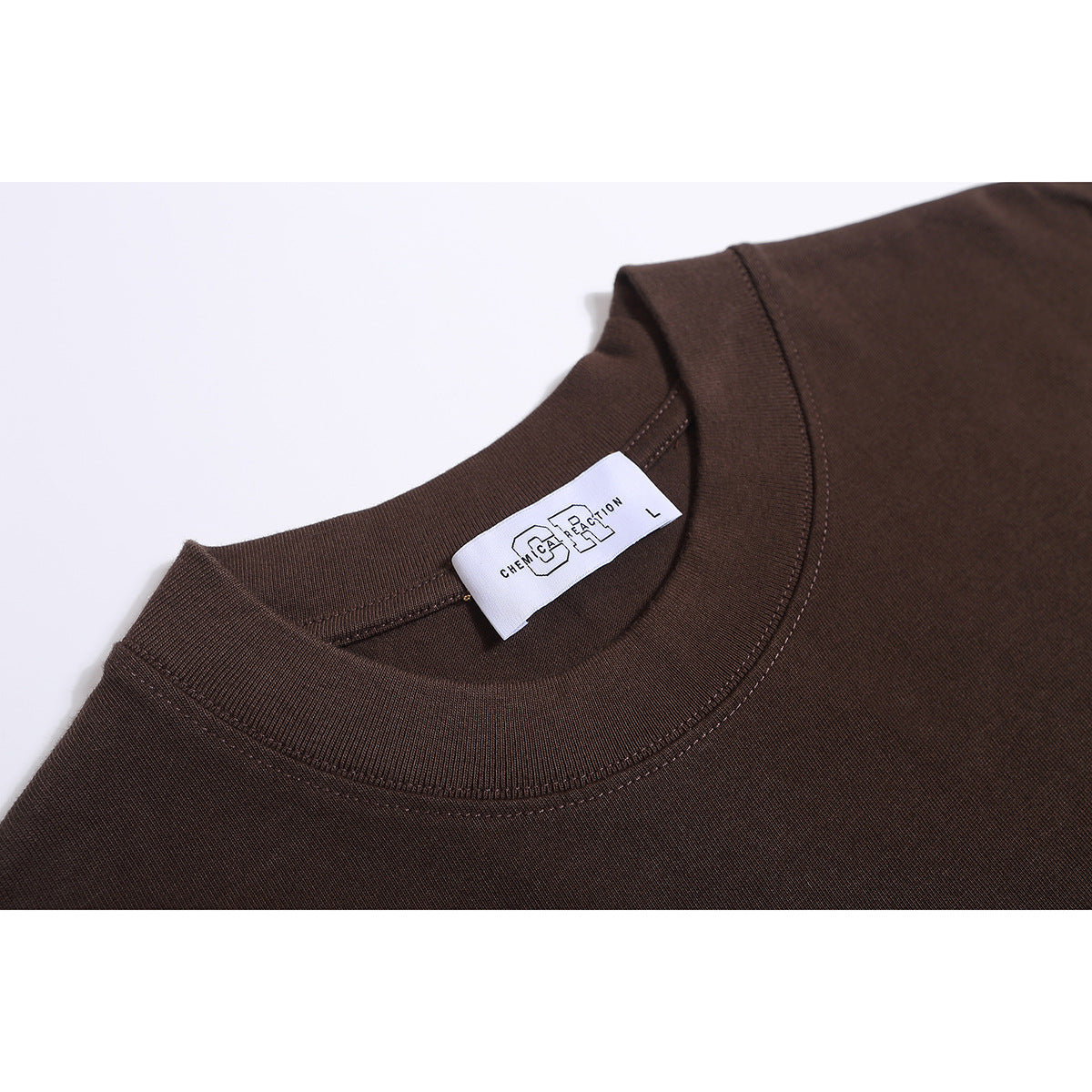 Close-up of a dark brown T-shirt's ribbed crew neck and attached white size label.
