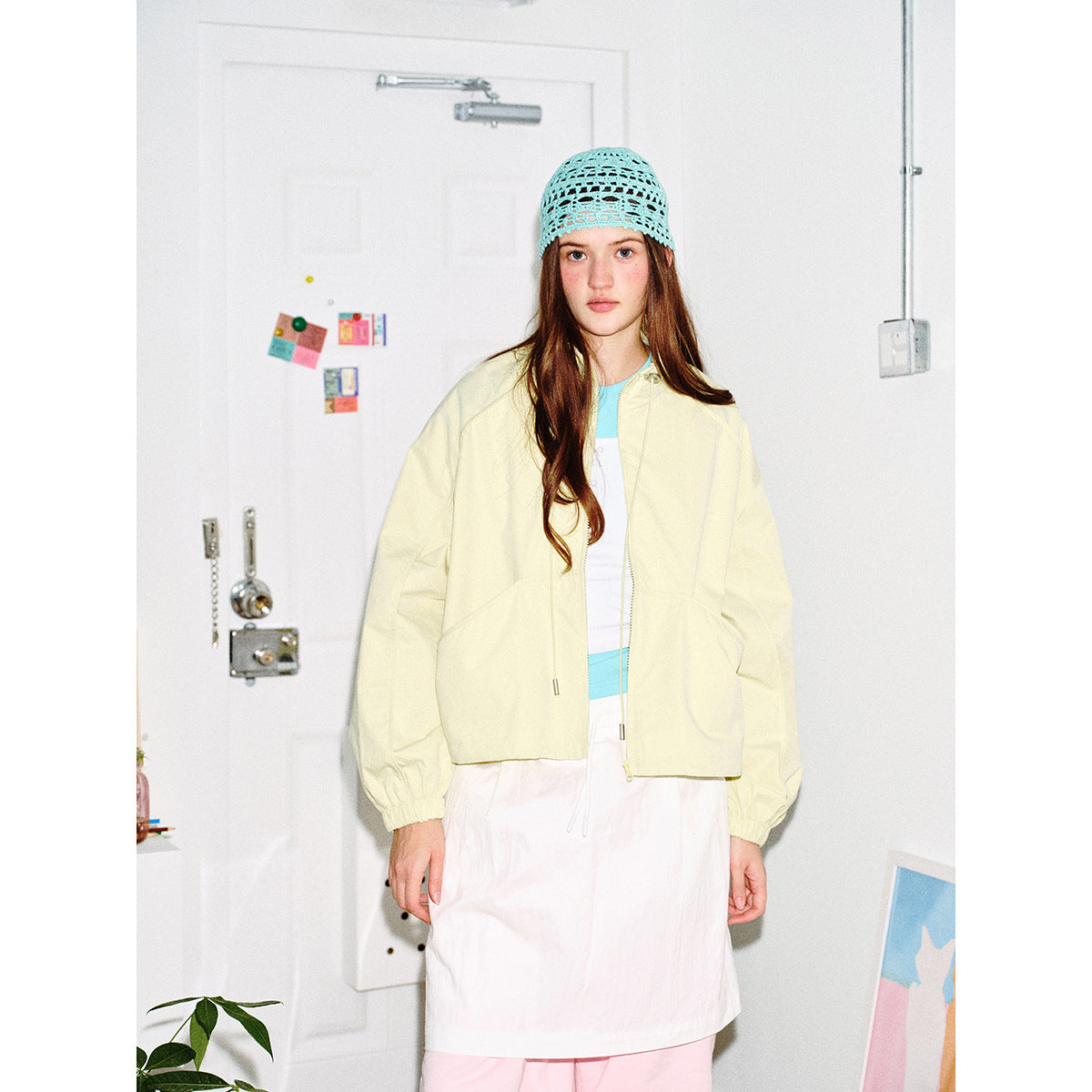 Model wearing a pale yellow cropped zip-front jacket with a high collar and gathered cuffs.