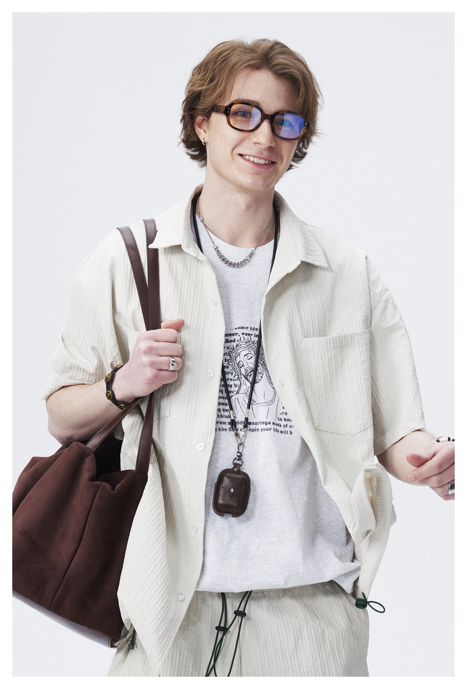 Model wearing an open ivory short-sleeve shirt and matching drawstring shorts over a printed gray T-shirt.