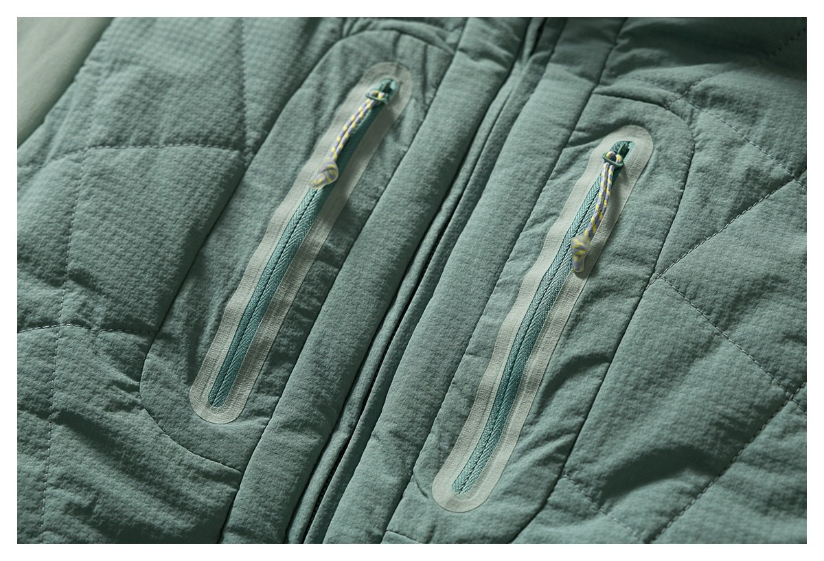 Close-up of two vertical zip pockets with cord pulls on a textured sage-green quilted jacket.