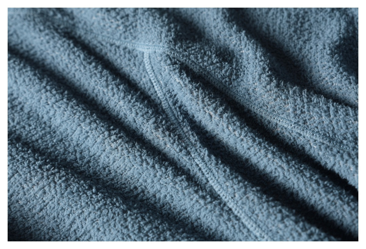 Close-up of blue textured fleece showing a curved stitched seam and fabric construction.
