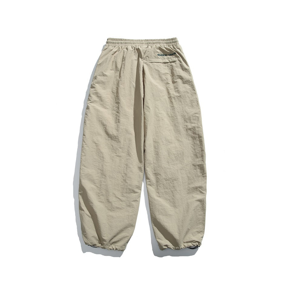 Rear view of light beige jogger pants with an elastic waist, small back pocket, and gathered ankle cuffs.