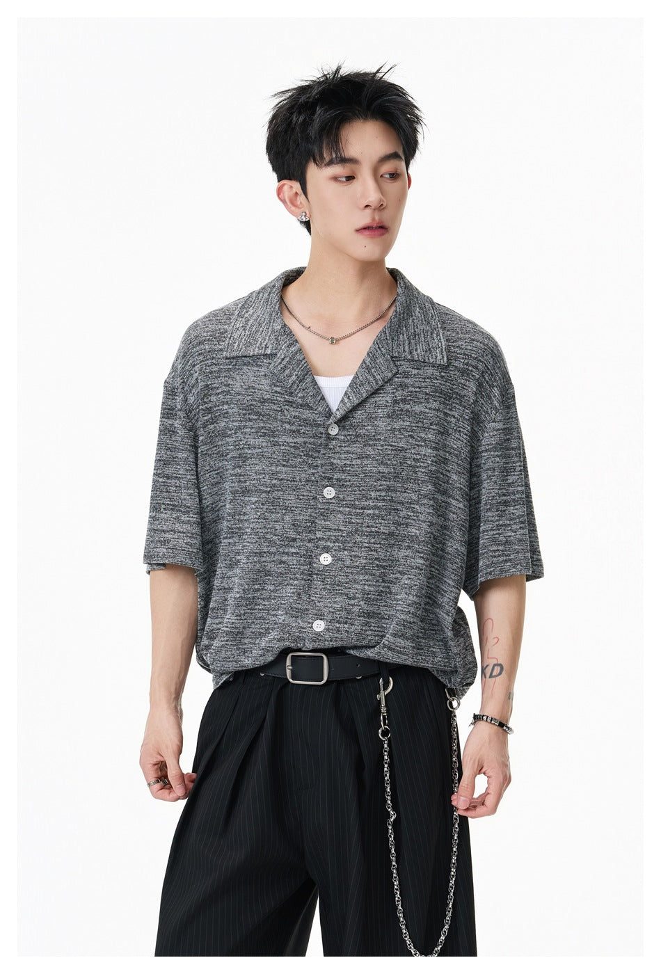 Model wearing a dark gray marled short-sleeve button-up shirt with a wide open collar and white buttons.