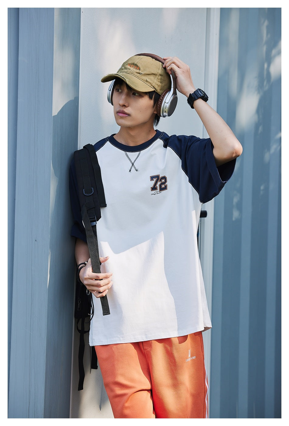 Model wearing a white T-shirt with navy raglan sleeves and a 72 chest graphic, shown from the front.