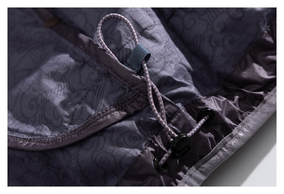 Close-up of a patterned jacket lining with an adjustable cord and black toggle at the edge.