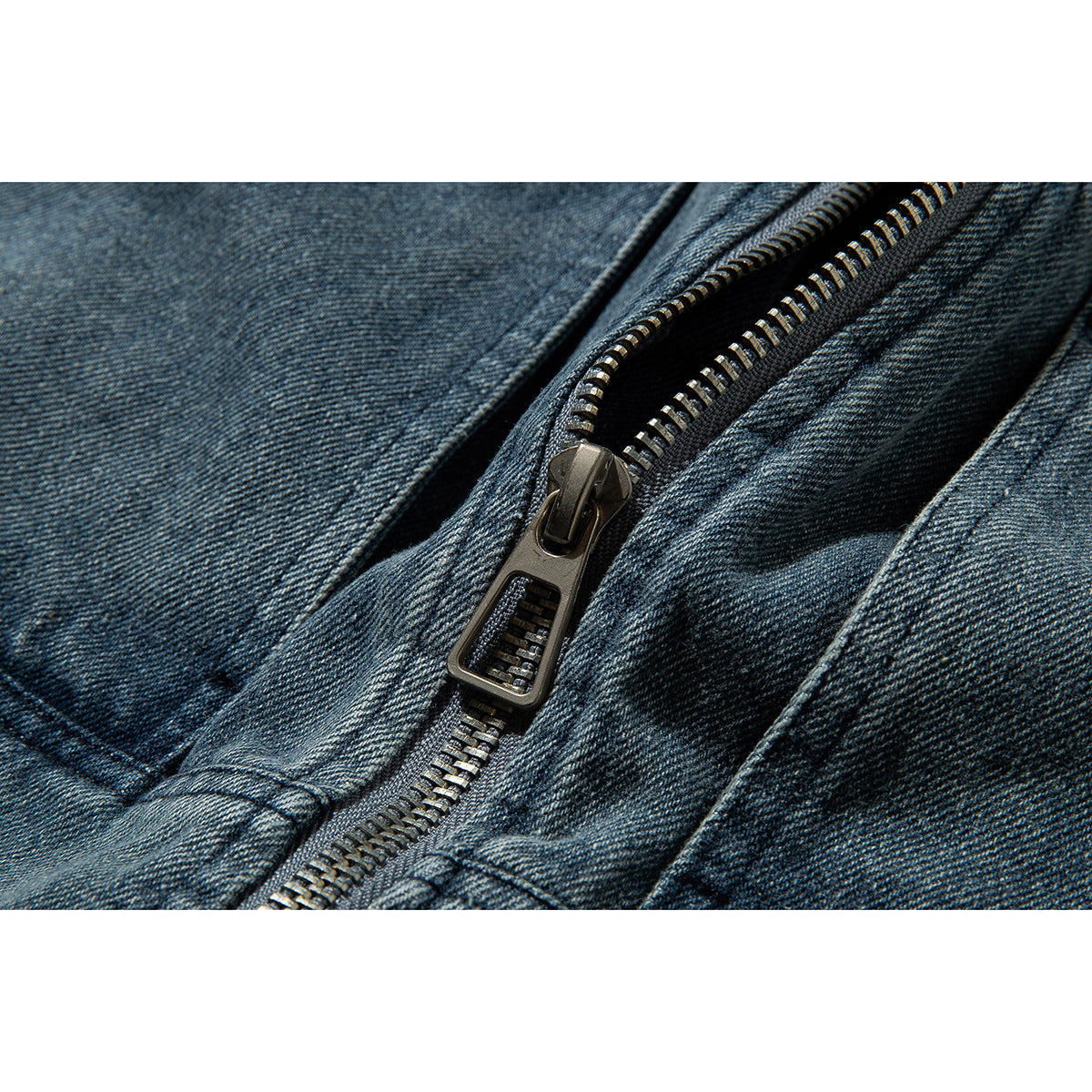 Close-up of the metal zipper and textured blue denim jacket fabric.