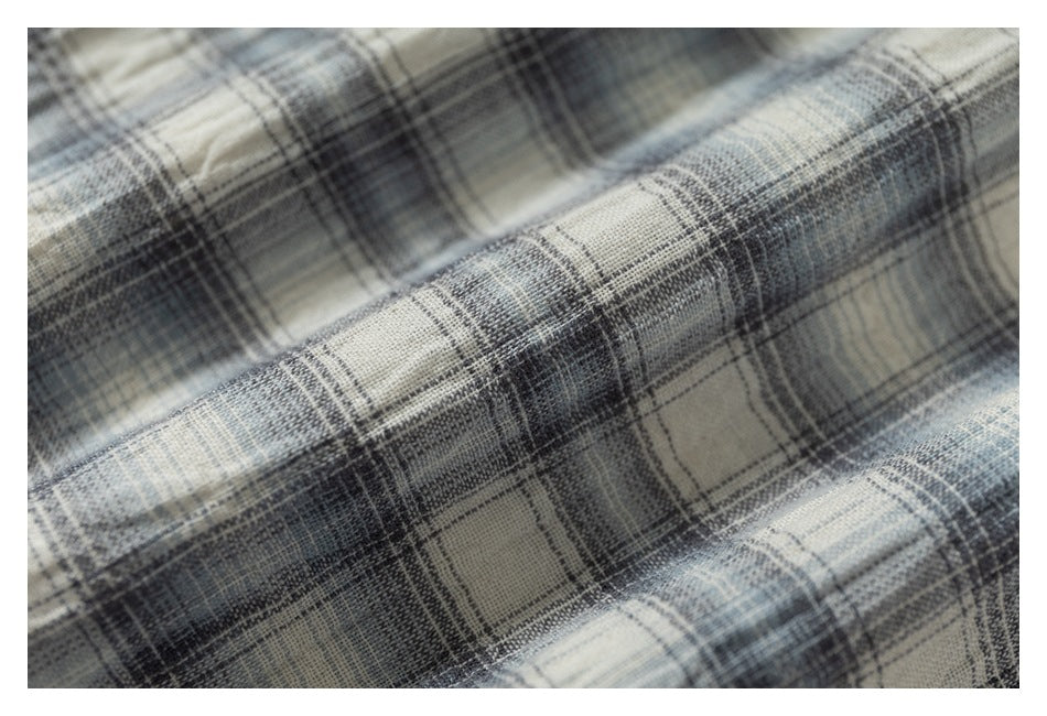 Macro view of the gray, blue, and cream plaid shirt fabric and its woven pattern.