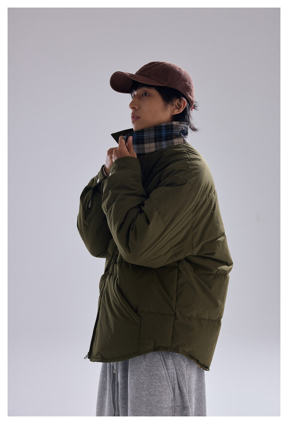 Model wearing an olive quilted jacket with a plaid scarf, shown in side view.