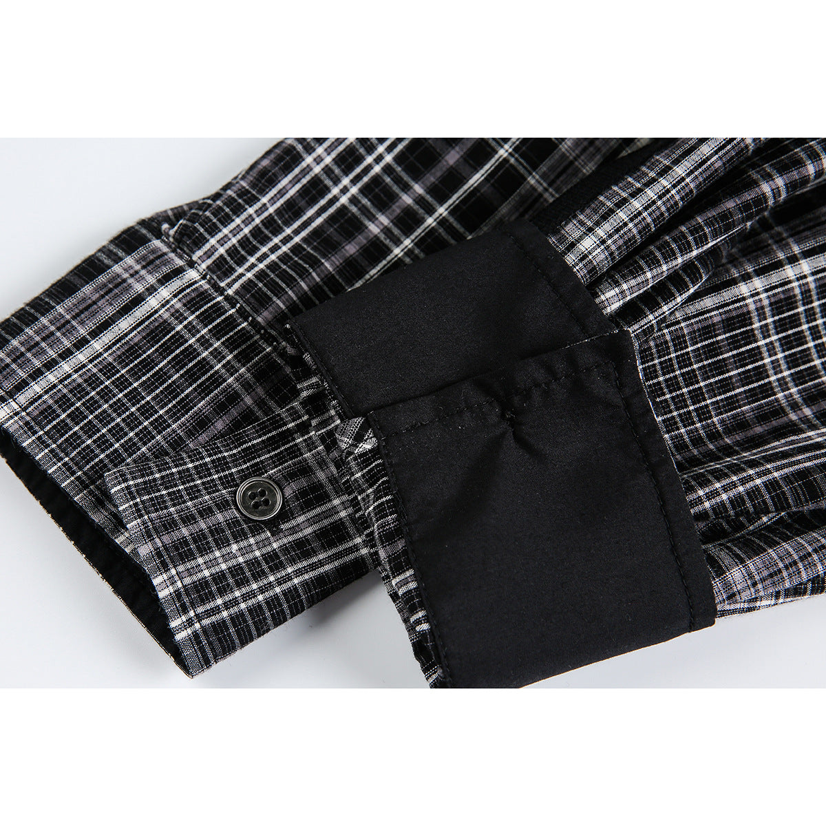 Close-up of a plaid shirt sleeve and buttoned cuff beside a wide solid-black cuff panel.