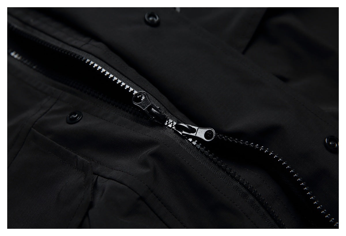 Close-up of a black garment with a partially open zipper and snap fasteners.