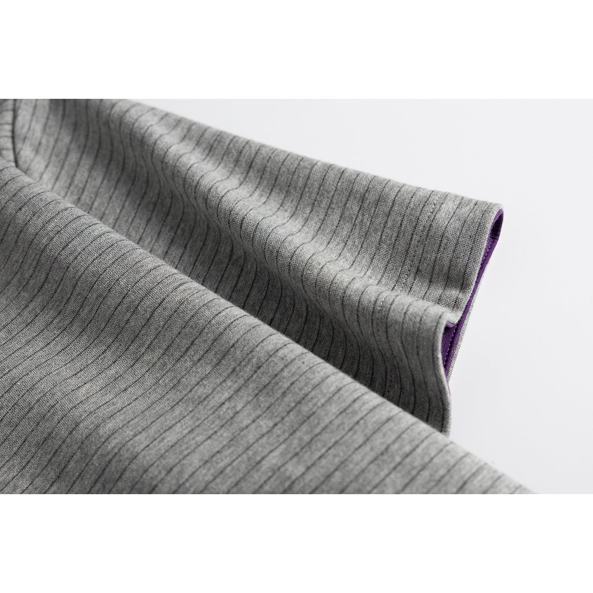 Close-up of gray striped shirt fabric folded to show the sleeve edge and purple inner facing.