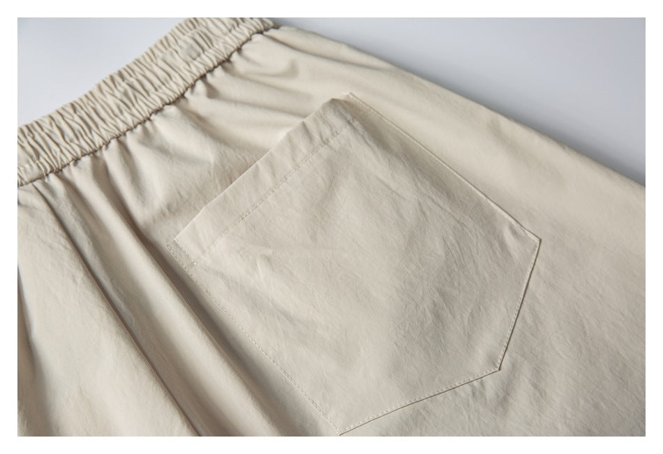 Close-up of a large stitched pocket on the back of cream shorts.