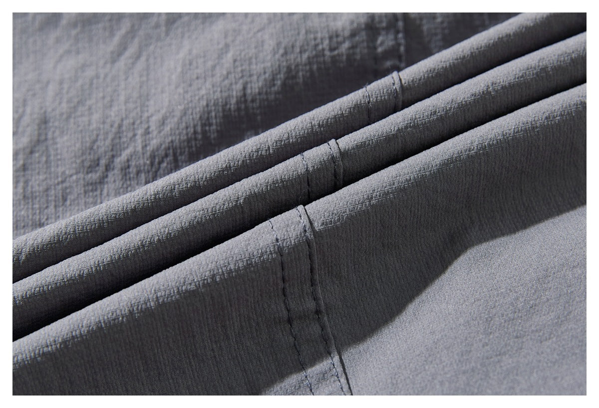 Close-up of folded gray fabric with stitched seams and a fine textured surface.