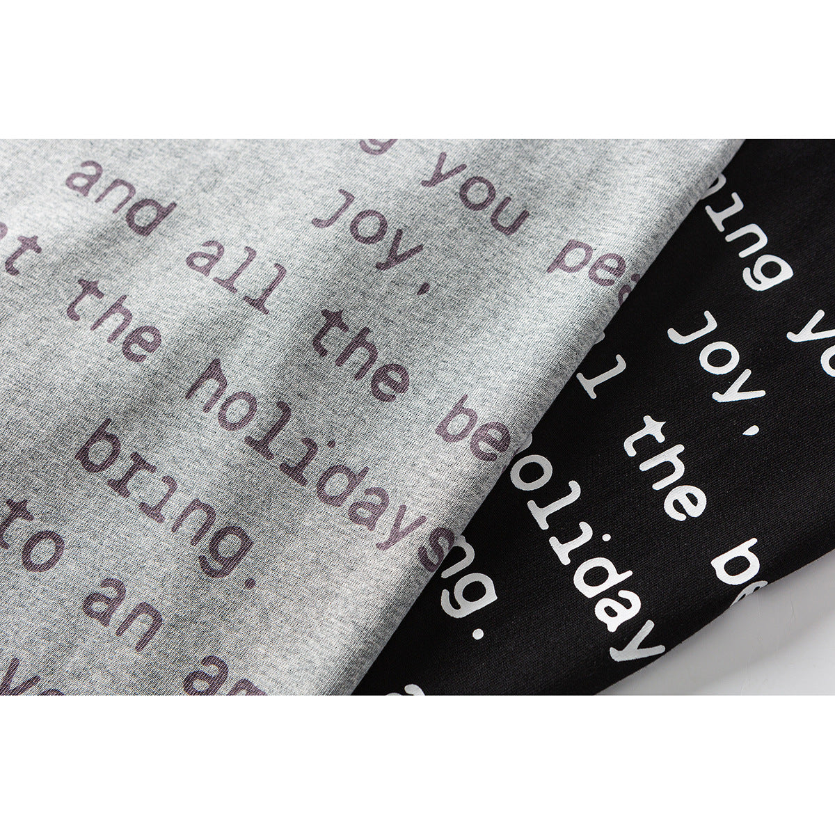 Close-up of gray and black T-shirt fabric with holiday greeting text printed in contrasting colors.