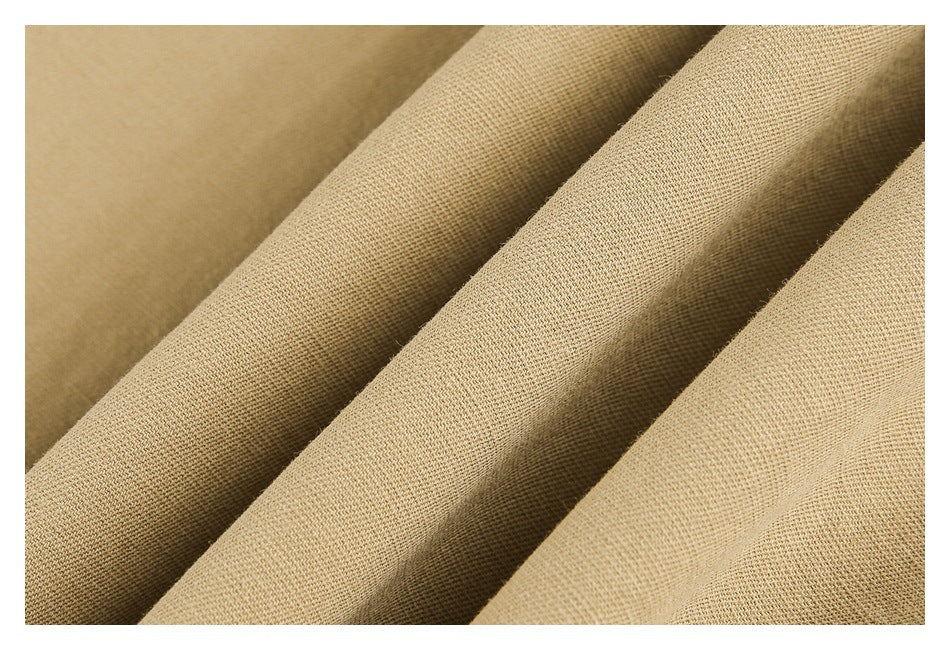 Close-up of tan fabric draped in folds, showing its woven surface texture.