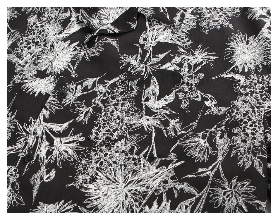 Close-up of a black shirt with white botanical floral print and dark buttons.