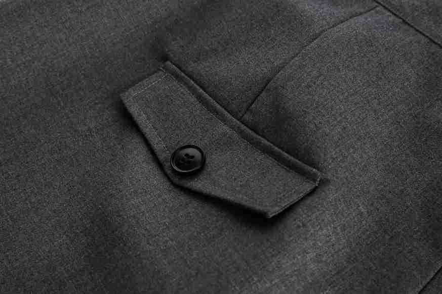 Close-up of a charcoal gray trouser pocket with a buttoned flap.