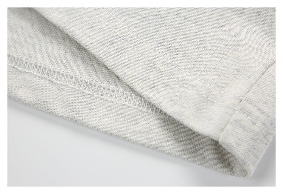 Close-up of a light heather-gray garment hem showing the overlock seam and stitching.