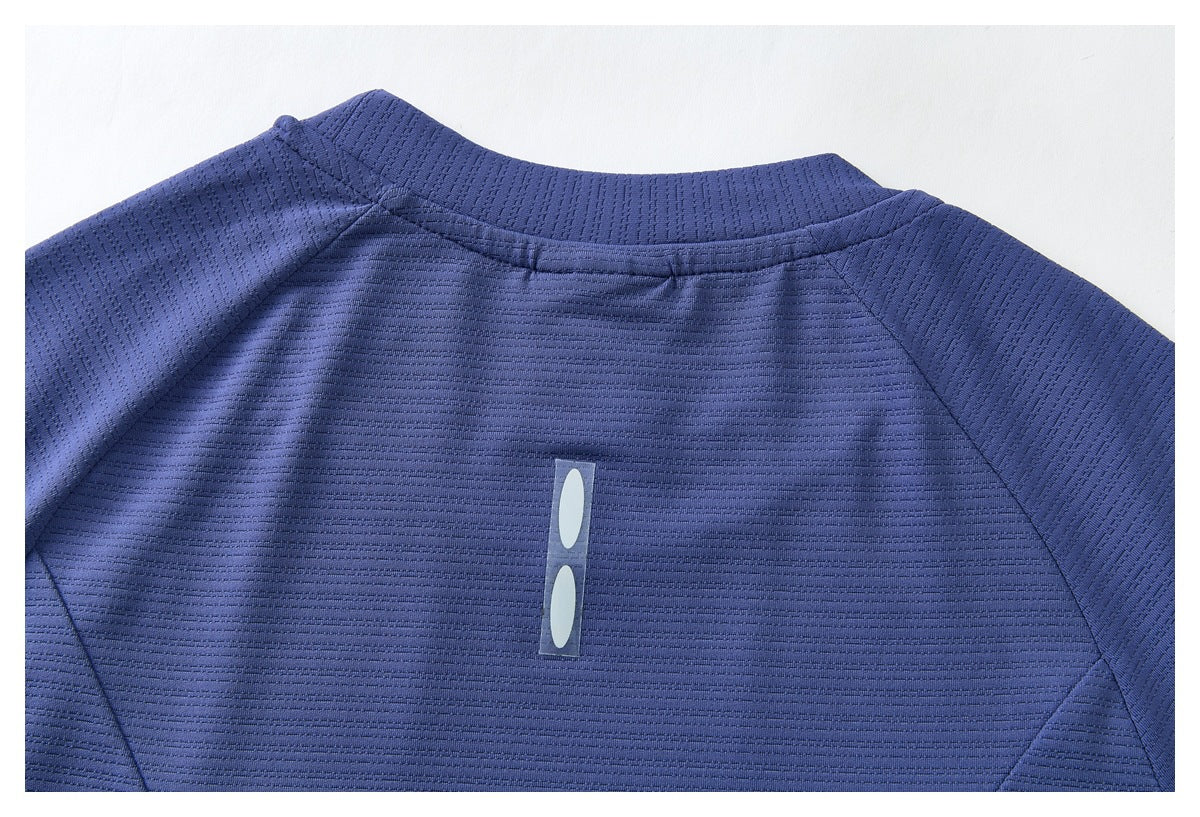 Upper back of a blue textured shirt with a short stand collar, raglan seams, and a small vertical reflective detail.