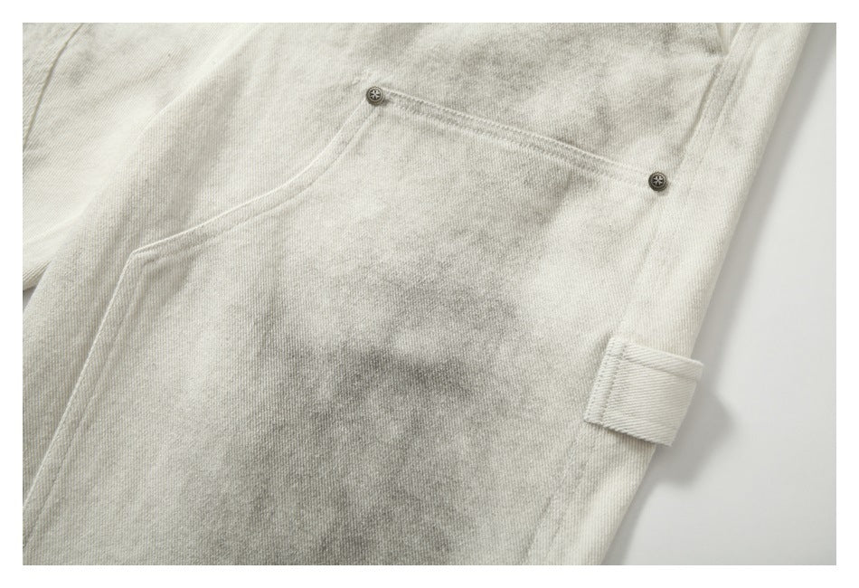 Close-up of cream-gray mottled trousers with a buttoned pocket flap and a small side tab.