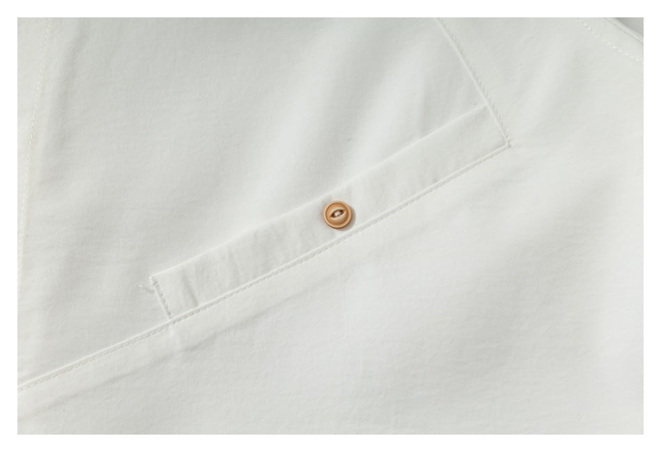 Close-up of an off-white garment with a tan button on a stitched placket.