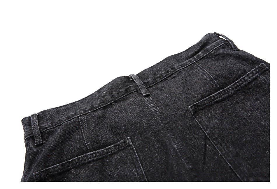 Partial back view of black denim shorts showing the waistband, belt loops, seams, and pocket edges.