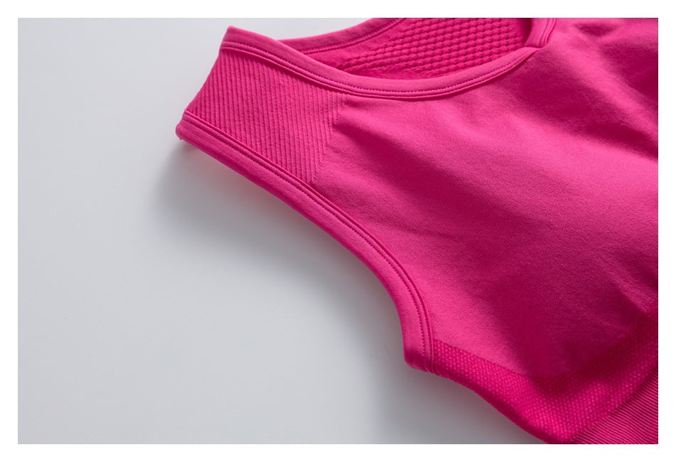 Close-up of a bright pink athletic top showing the neckline, shoulder seam, and textured side panel.