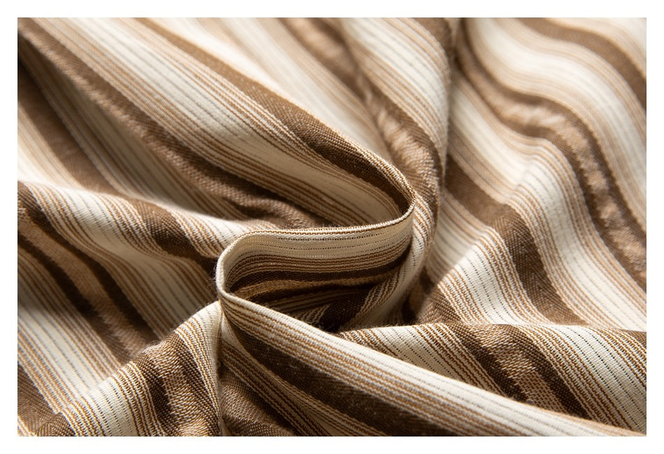 Close-up of draped tan, brown, and cream striped fabric showing its fine woven pattern.