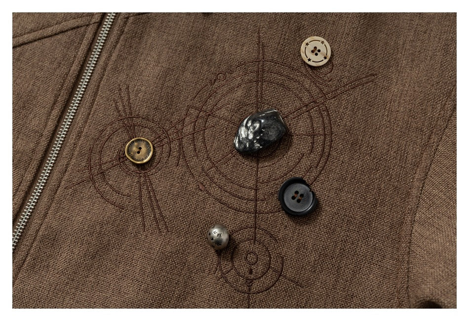 Close-up of decorative face-like stitching with assorted buttons on the brown jacket.