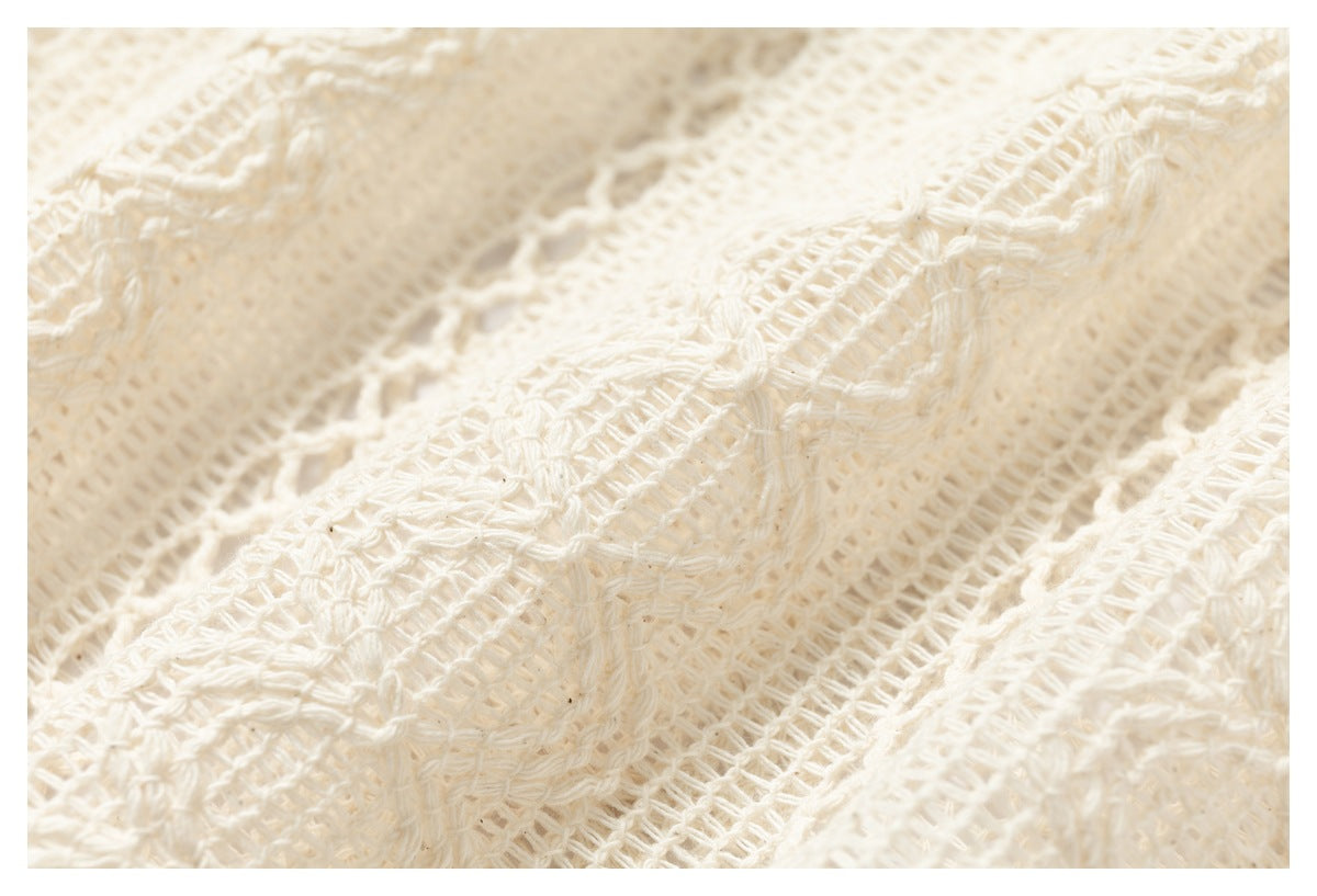 Macro view of the cream garment's open-knit weave with raised decorative patterns.
