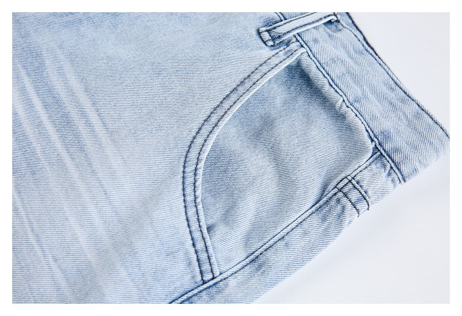 Close-up of a light-wash denim jeans pocket with curved stitching and a belt loop.
