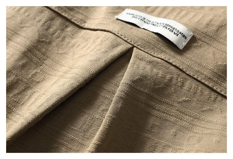 Close-up of the tan shirt's folded fabric and sewn-in English text label.