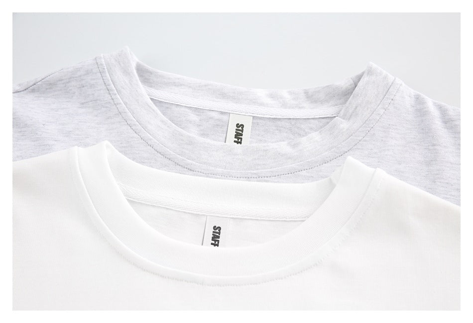 Close-up of white and light gray T-shirt crew necklines with small STAFF neck labels.